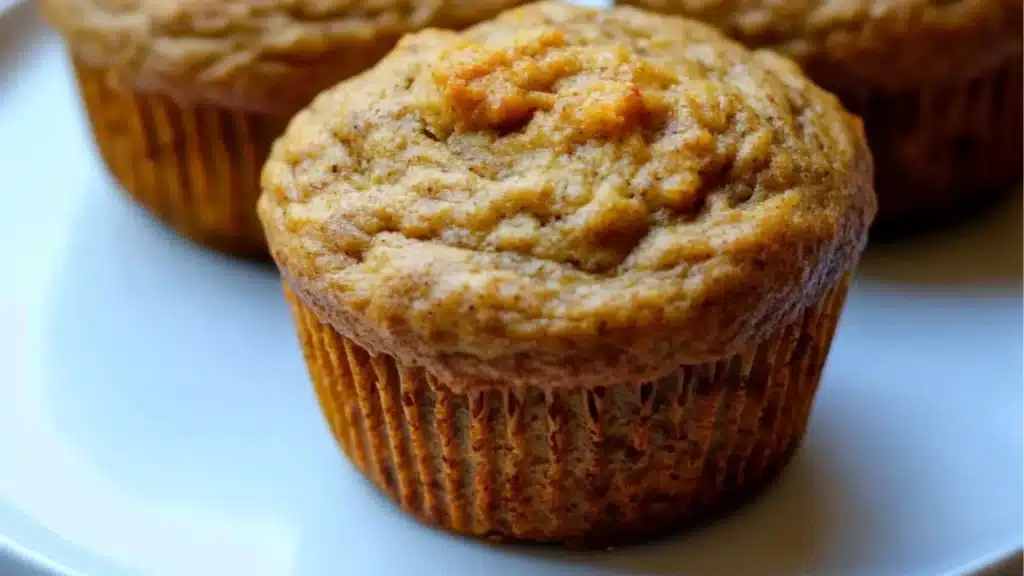 two muffins with text overlay that reads greek yogurt and high protein pumpkin muffins